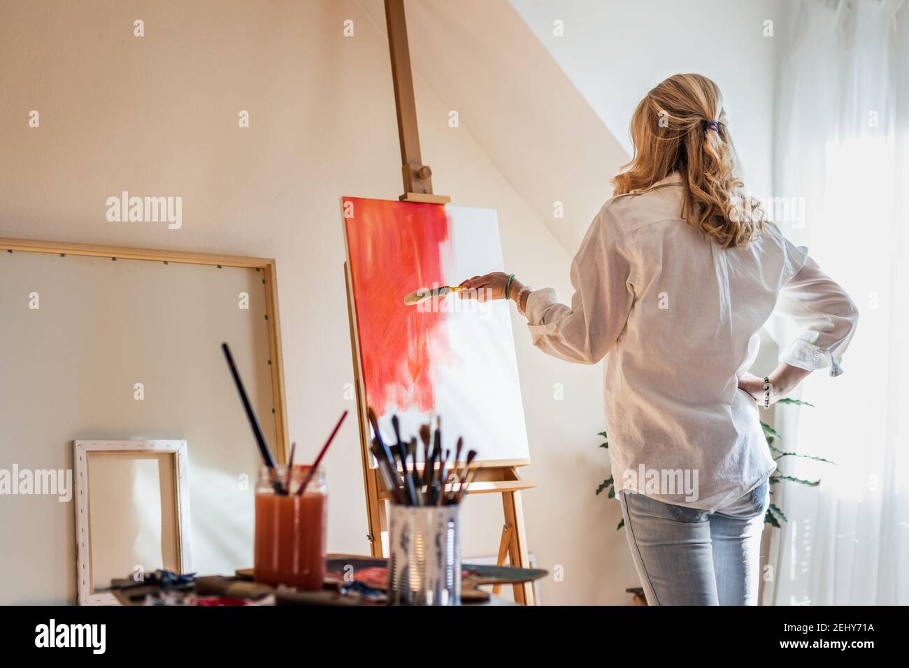 Female artist painter is looking at her paintings and trying find the ...