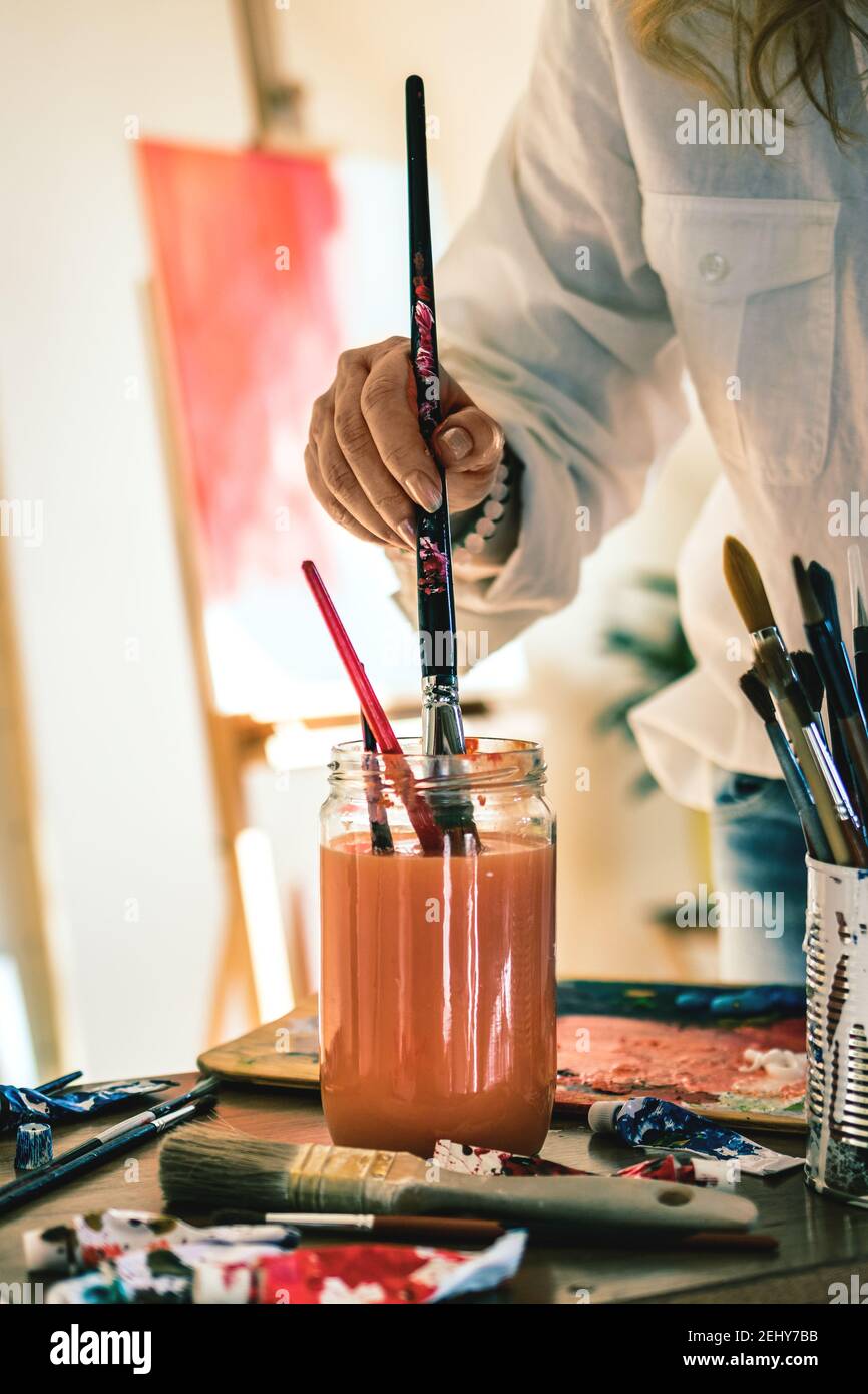 Woman artist cleaning paintbrush during working on her abstract