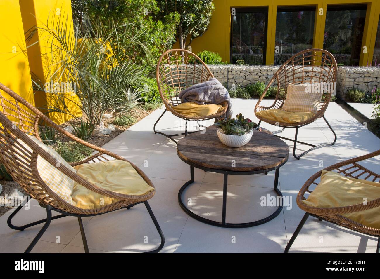 working from home garden office studio Mediterranean climate garden modern grey paved stone paving patio rattan garden furniture table chairs UK Stock Photo