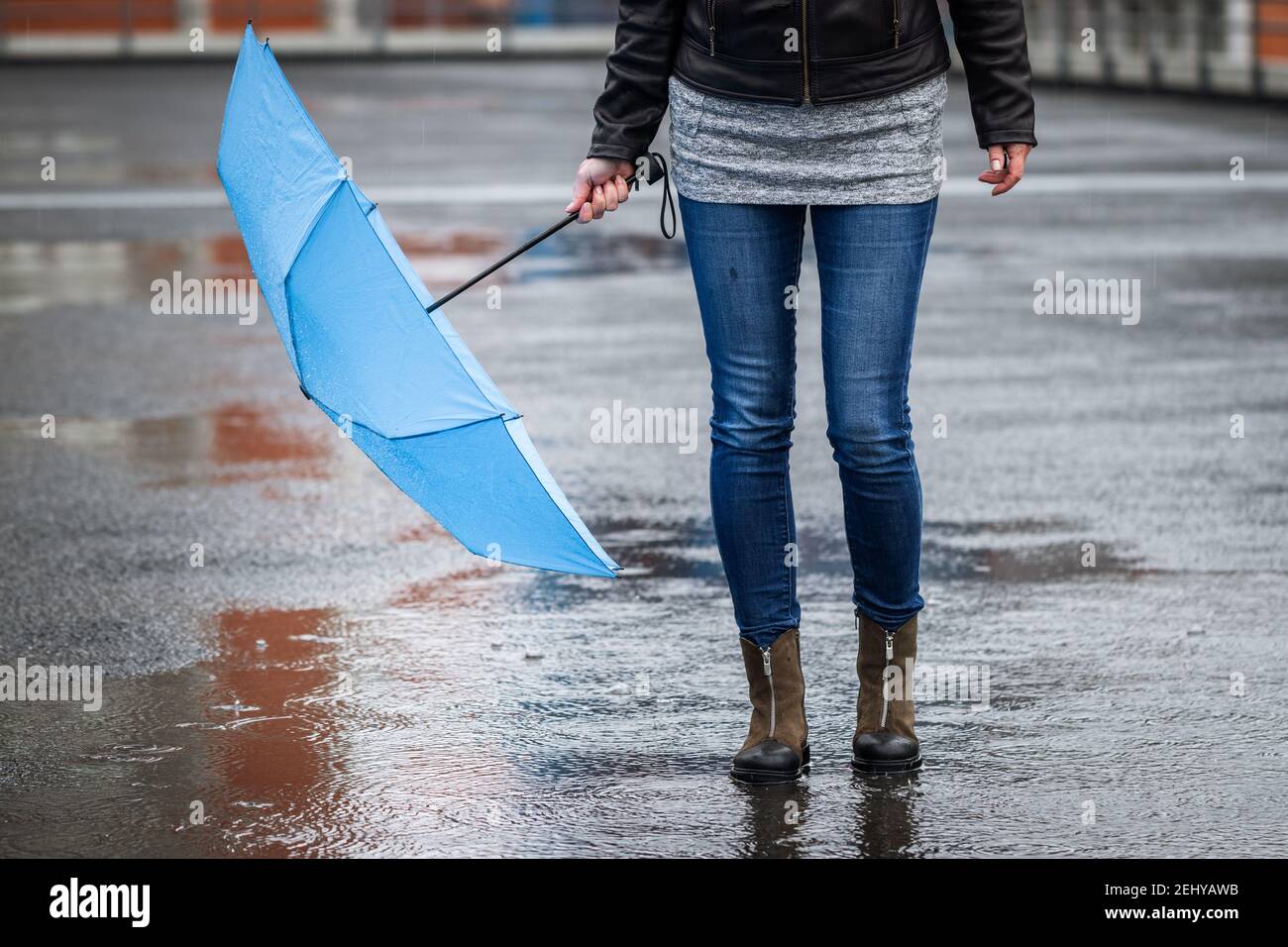 Woman with umbrella walking in rain at city street. Female legs wearing  jeans and waterproof leather boot Stock Photo - Alamy