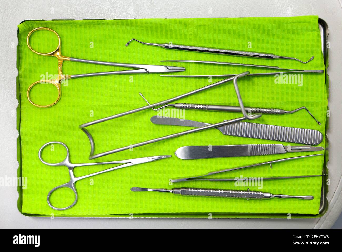 A close up of Doctors Tools on a Metal Tray with Green Paper Stock Photo