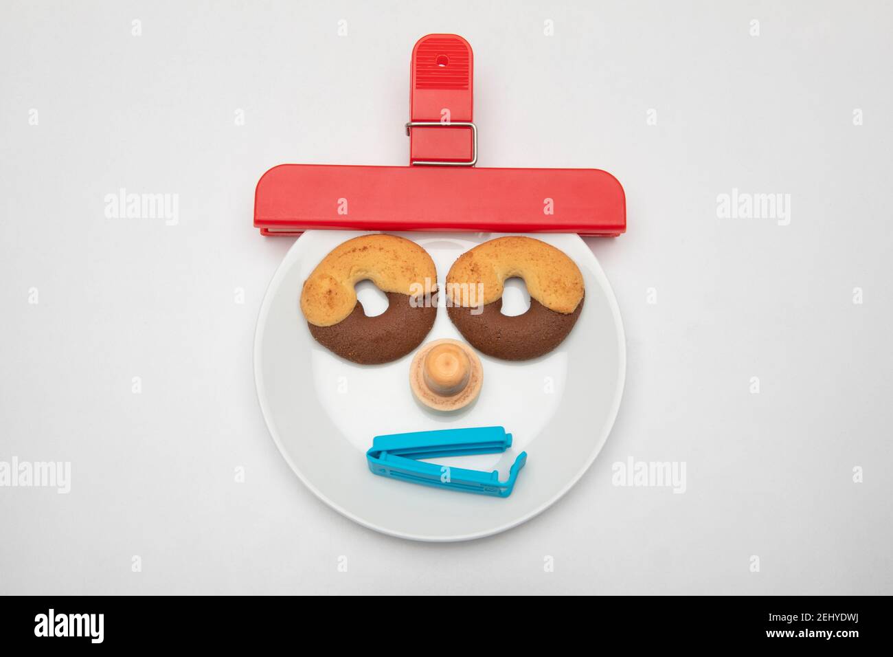 a face made of biscuits on a plate with bag closure clips Stock Photo