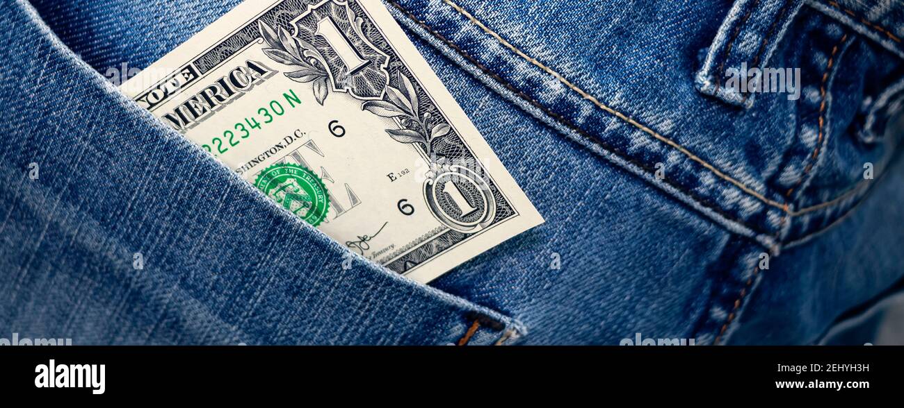 Banner with one Dollar bill in the back pocket of jeans. One buck in a denim pocket. Close-up Stock Photo