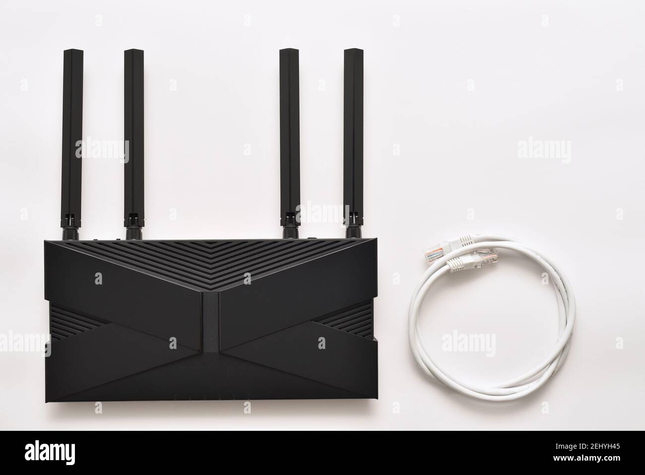 Modern black wi-fi 6 router on a white background with ethernet cable Stock Photo