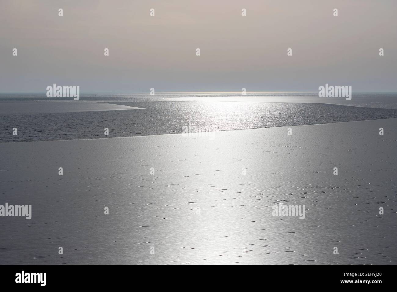 Silver colored backlight on the ice and water surface of the IJsselmeer, North Holland, The Netherlands. Stock Photo