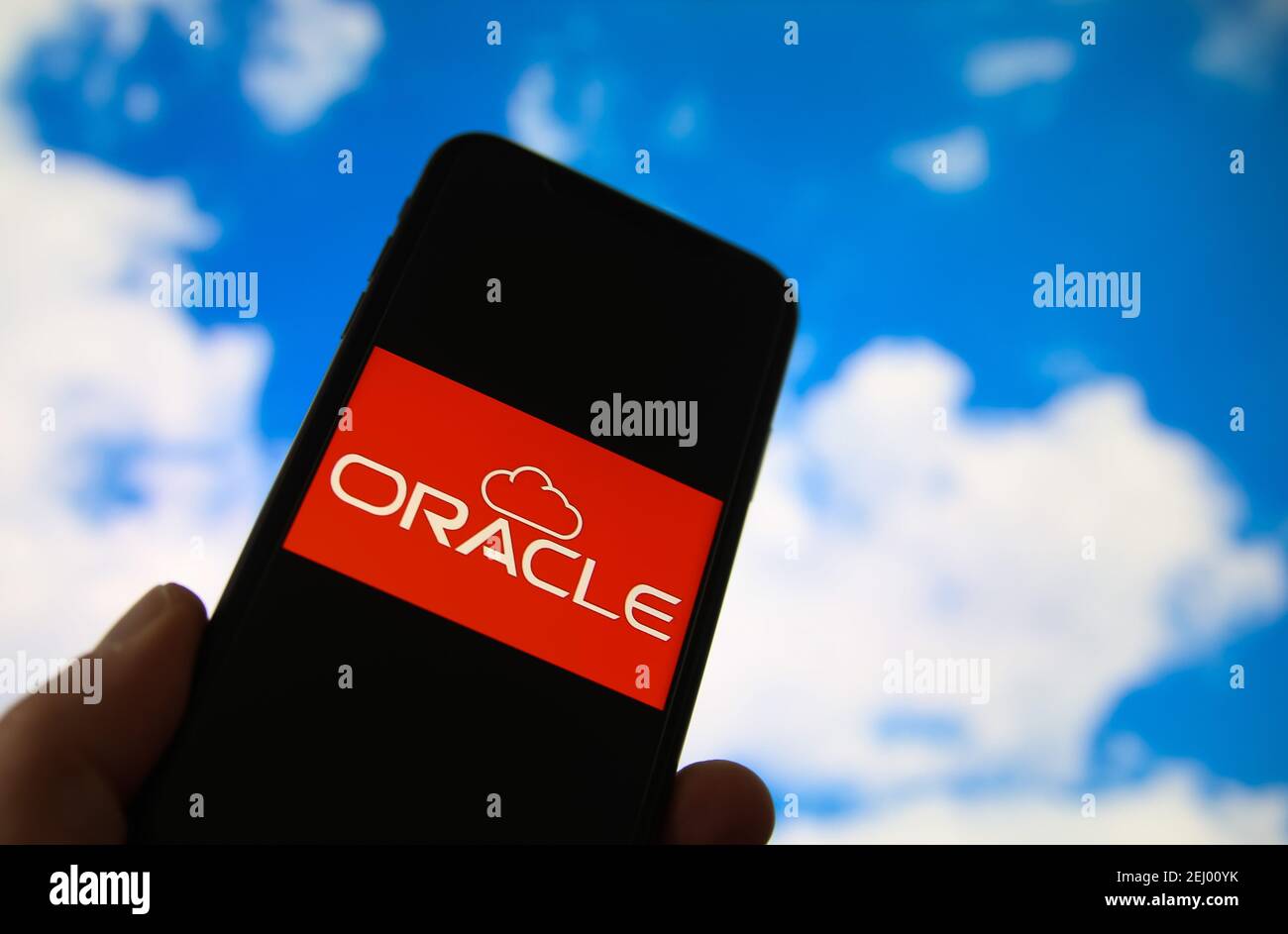 Viersen, Germany - February 9. 2021: Closeup of smartphone with logo lettering of cloud computing provider service oracle, blurred sky and cloud backg Stock Photo