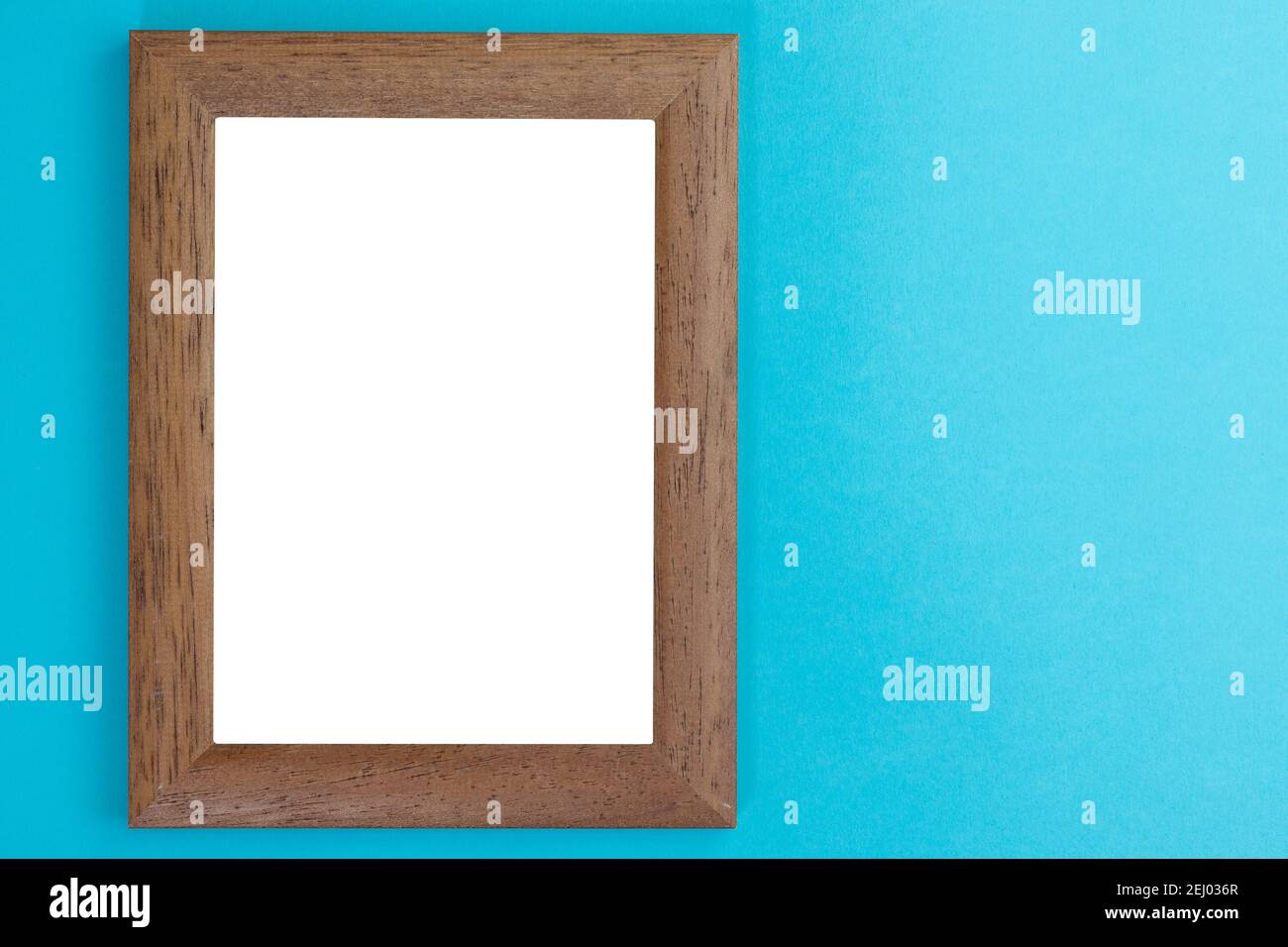 wooden picture frame with white interior on light blue wall Stock Photo