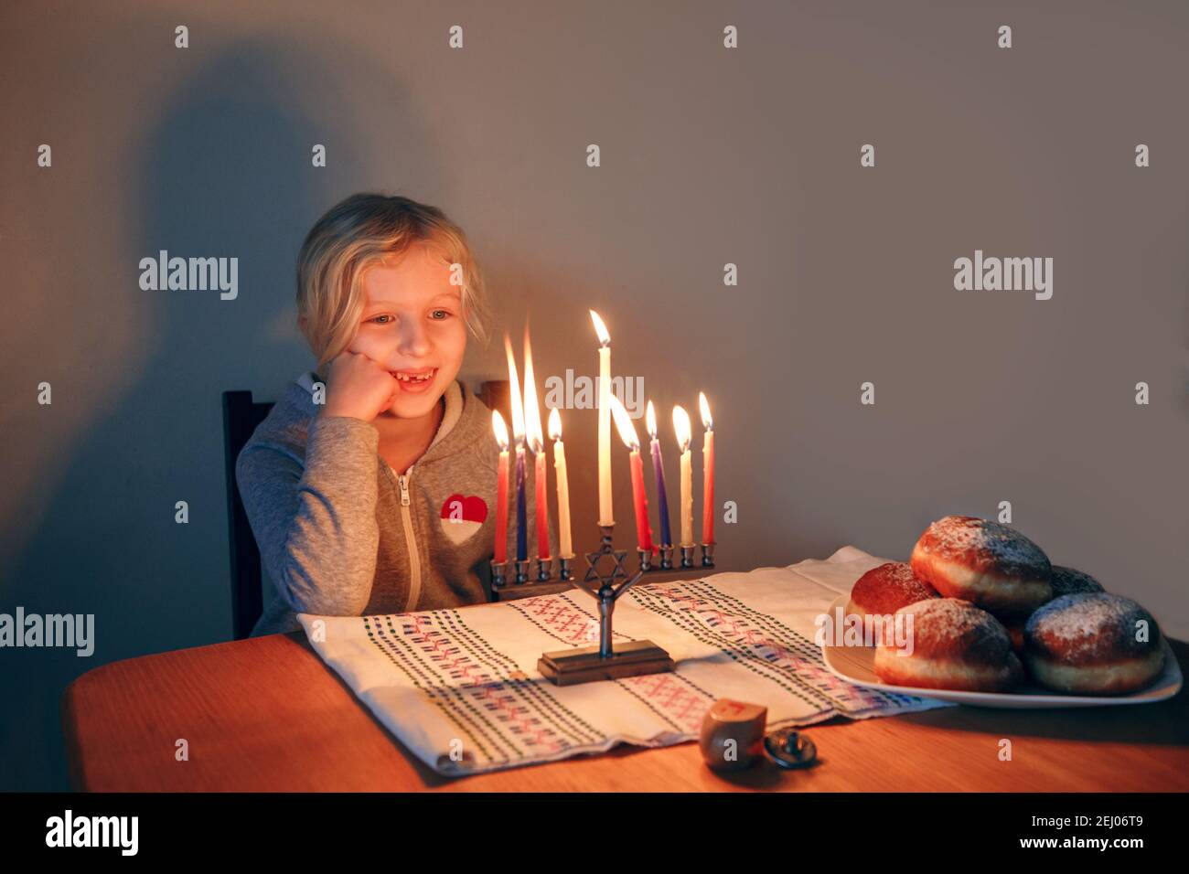 Girl lighting candles on menorah for traditional winter Jewish Hanukkah