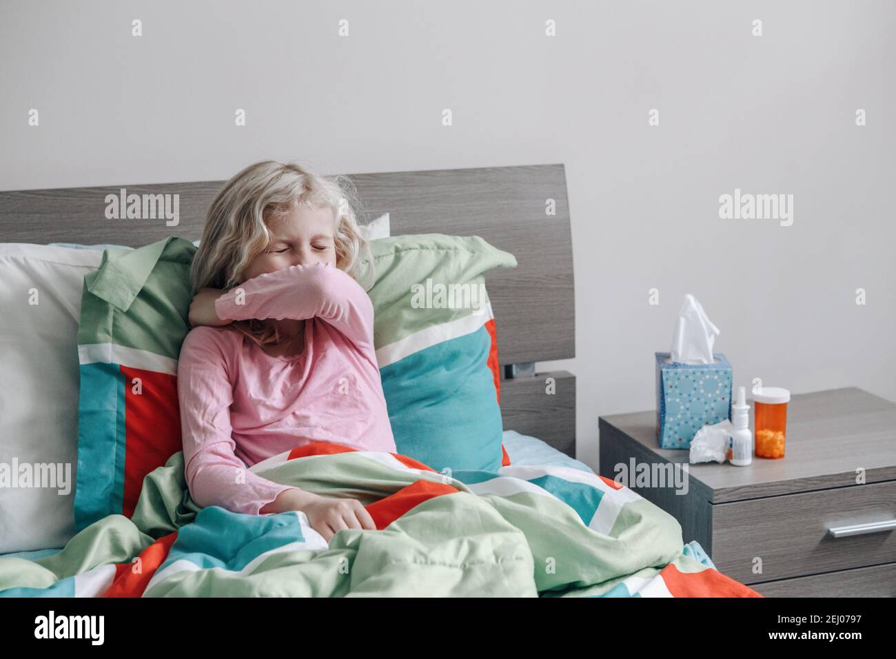 Sick ill kid girl with fever lying in bed at home with flu, fever