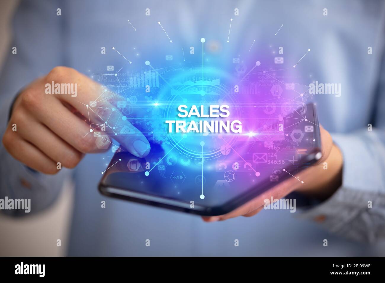 Businessman holding a foldable smartphone with SALES TRAINING inscription, new business concept Stock Photo