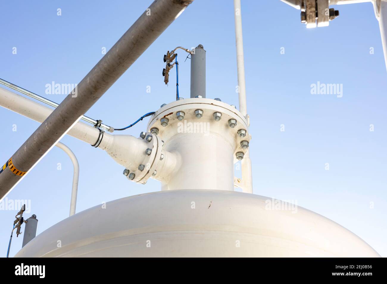 industrial background with pipes, joints, bolts and pressure tank color white with blue sky as background Stock Photo