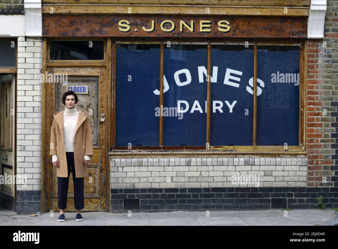 Young woman standing in from of urban store front with closed sign on door in London. Stock Photo