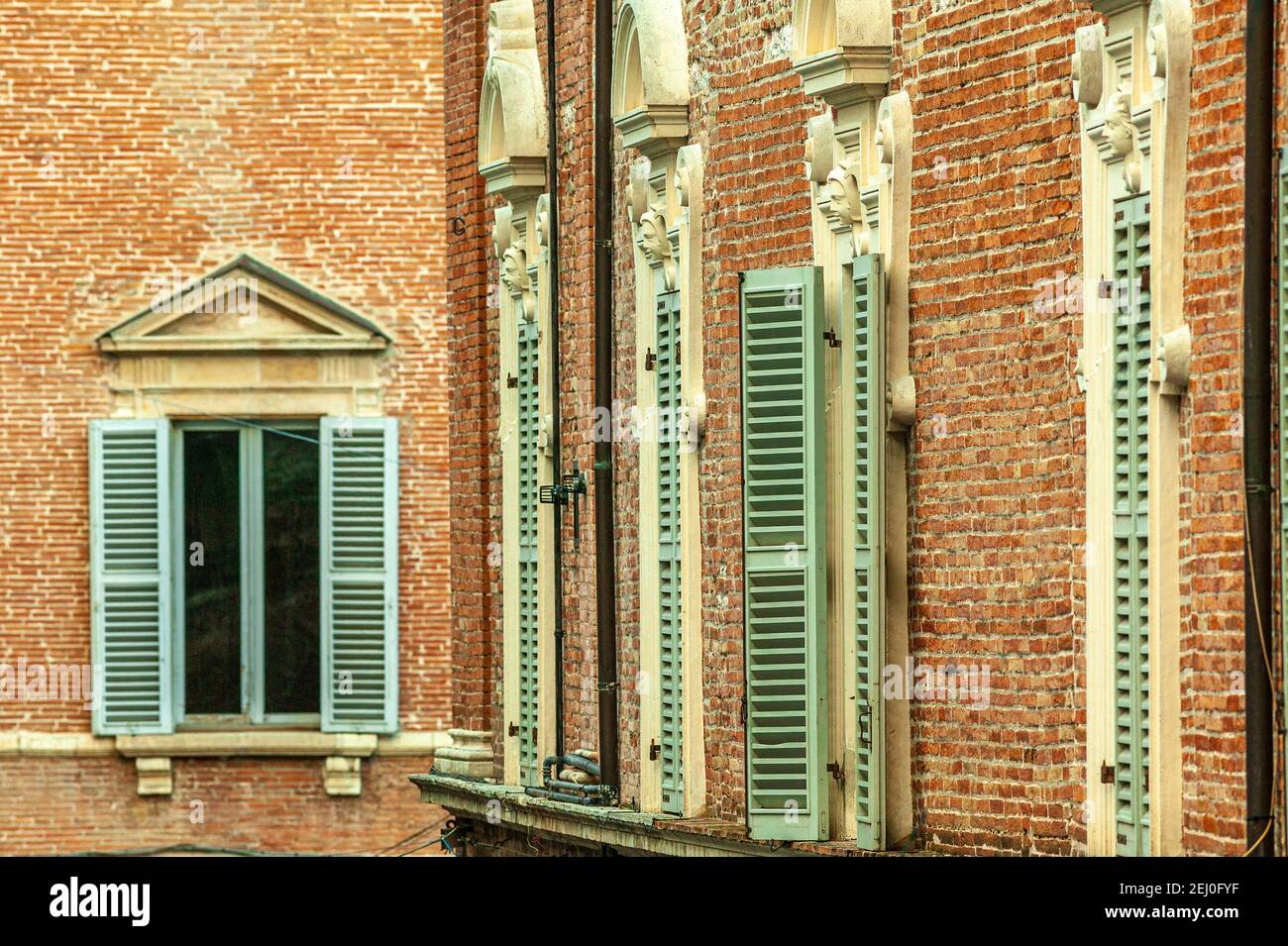 Wooden windows, painted green in a red brick wall of a medieval palace. Fabriano, province of Ancona, Marche, Italy, Europe Stock Photo