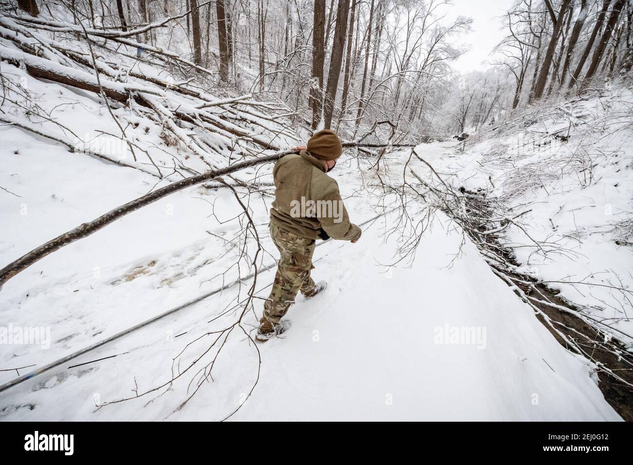 Ceredo, United States. 19th Feb, 2021. A U.S. soldier with the West Virginia National Guard clears debris from a winter storm off a road February 19, 2021 in Ceredo, Wayne County, West Virginia. A large winter storm system earlier in the week left more than 90,000 West Virginians without electric throughout the region, felling trees and making remote roads impassable. Credit: Planetpix/Alamy Live News Stock Photo