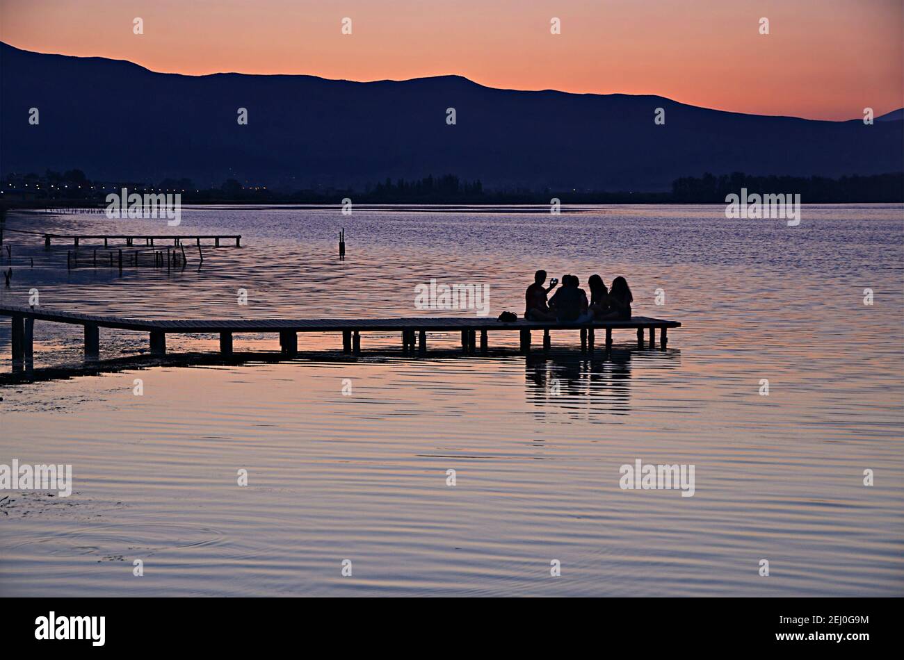 Sunrise landscape with young people silhouettes on the small wooden Pier of Missolonghi Lagoon in Aetolia-Acarnania, Greece. Stock Photo