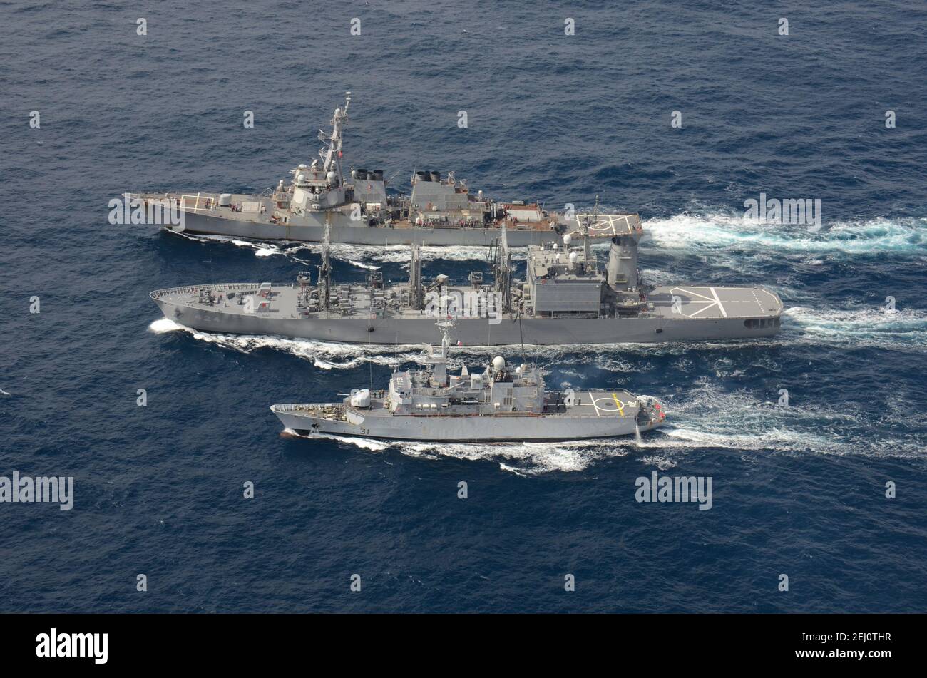 The U.S. Navy Arleigh Burke-class guided-missile destroyer USS Curtis Wilbur, top, conducts a replenishment-at-sea with the Japan Maritime Self-Defense Force Towada-class replenishment ship JS Hamana, center, and French Floreal-class light frigate FNS Prairial during joint operations February 19, 2021 in the Pacific Ocean. Stock Photo