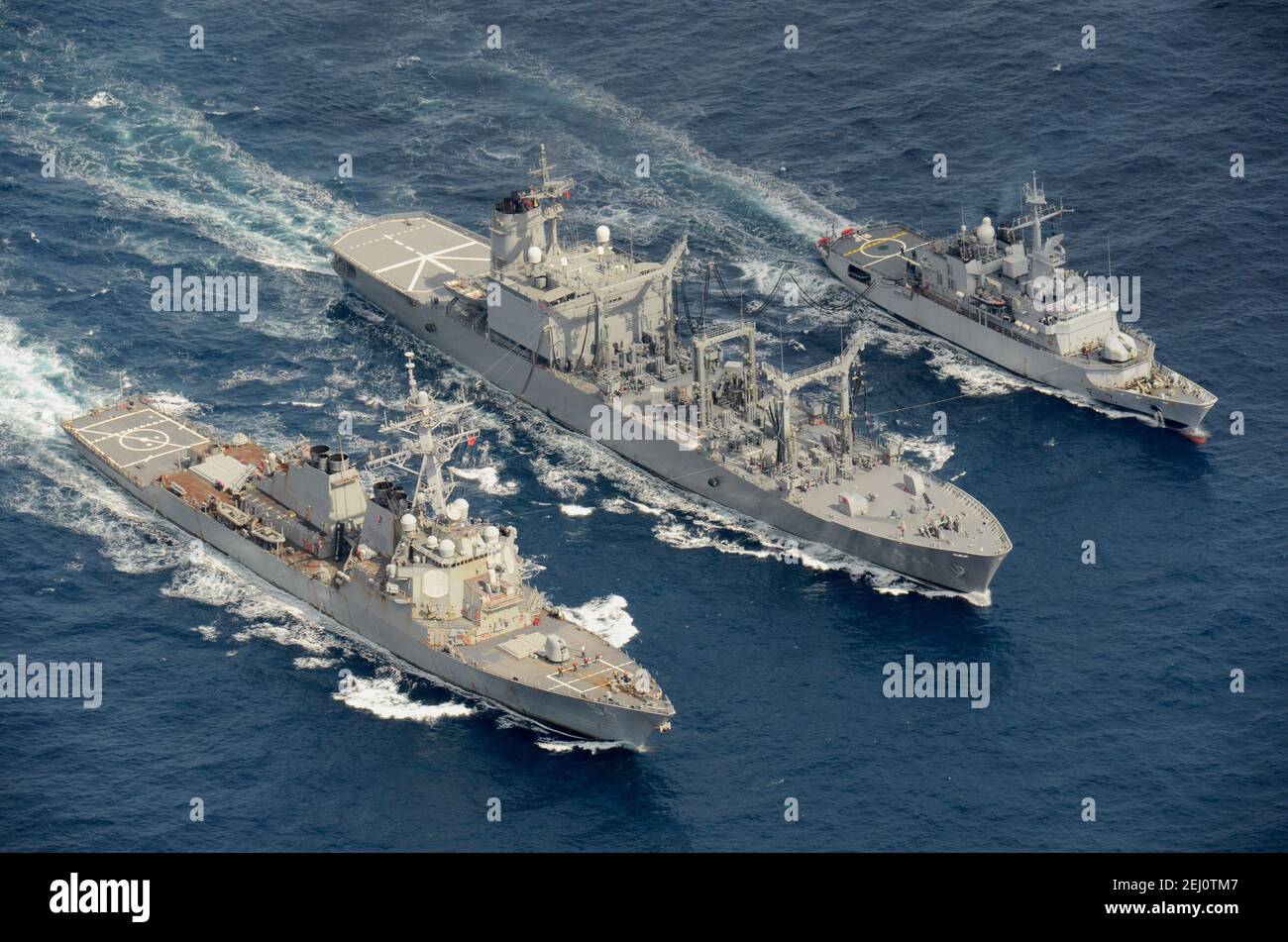 The U.S. Navy Arleigh Burke-class guided-missile destroyer USS Curtis Wilbur, left, conducts a replenishment-at-sea with the Japan Maritime Self-Defense Force Towada-class replenishment ship JS Hamana, center, and French Floreal-class light frigate FNS Prairial during joint operations February 19, 2021 in the Pacific Ocean. Stock Photo