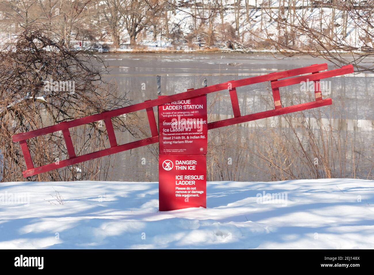 bright red ice rescue ladder station with a danger warning of thin ice in Inwood HIll Park in New York after a snowstorm with snow covered ground Stock Photo