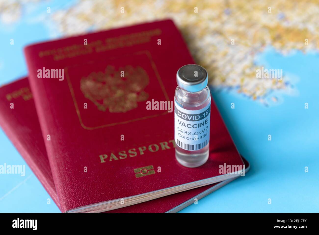 Coronavirus, travel and vaccine concept, bottle of COVID-19 vaccine and passports on tourist map. COVID vaccination due to restrictions and lockdown. Stock Photo