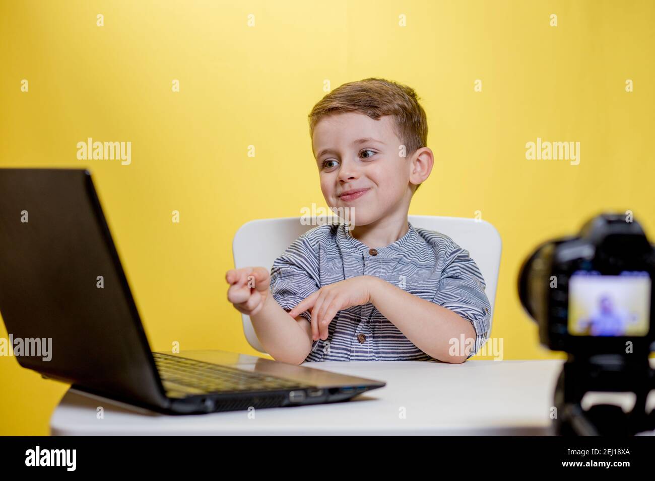 Kid blogger filming video on camera working with the laptop, at home ...