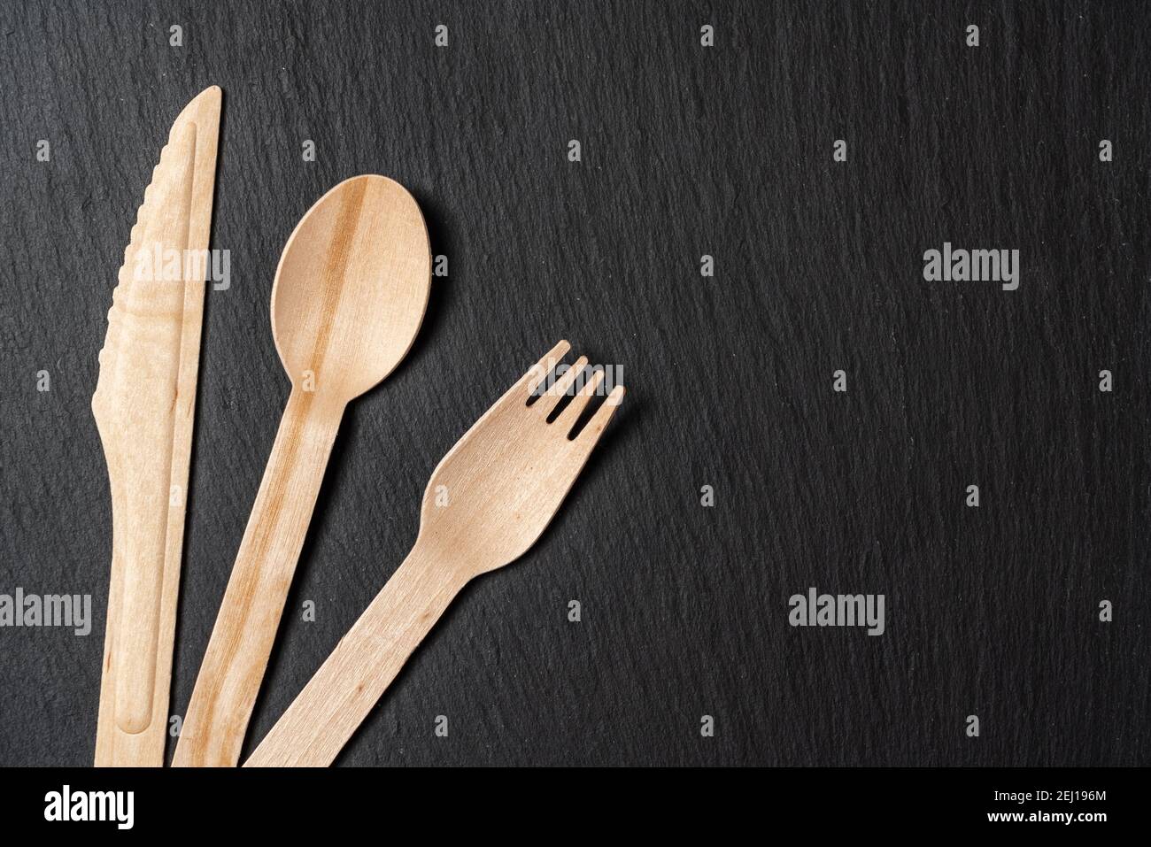 Disposable biodegradable tableware made of wood spoon, knife and fork on marble texture. Close-up. Stock Photo