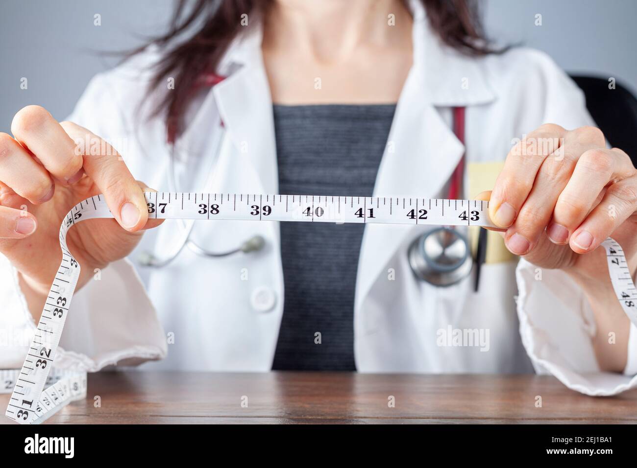 Close up isolated image of a caucasian doctor holding a tape measure in her hands which shows 40 inches as abdominal circumference upper limit in heal Stock Photo