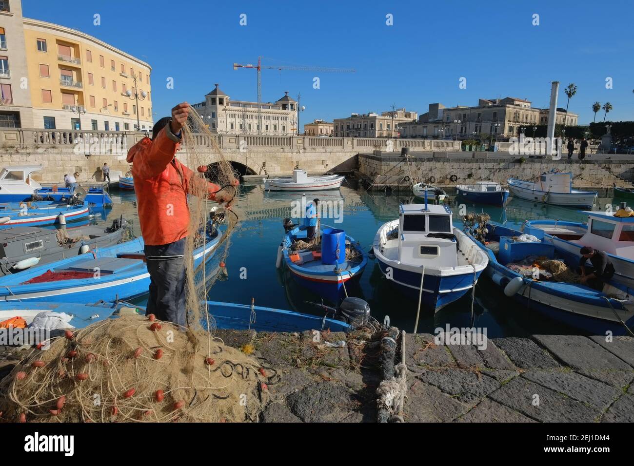 SIRACUSA, ITALY - JENUARY 03: fishing boats and fishermans in the darsena of Ortigia, Old Town of Siracusa in Sicily. The fisherman in foreground chec Stock Photo