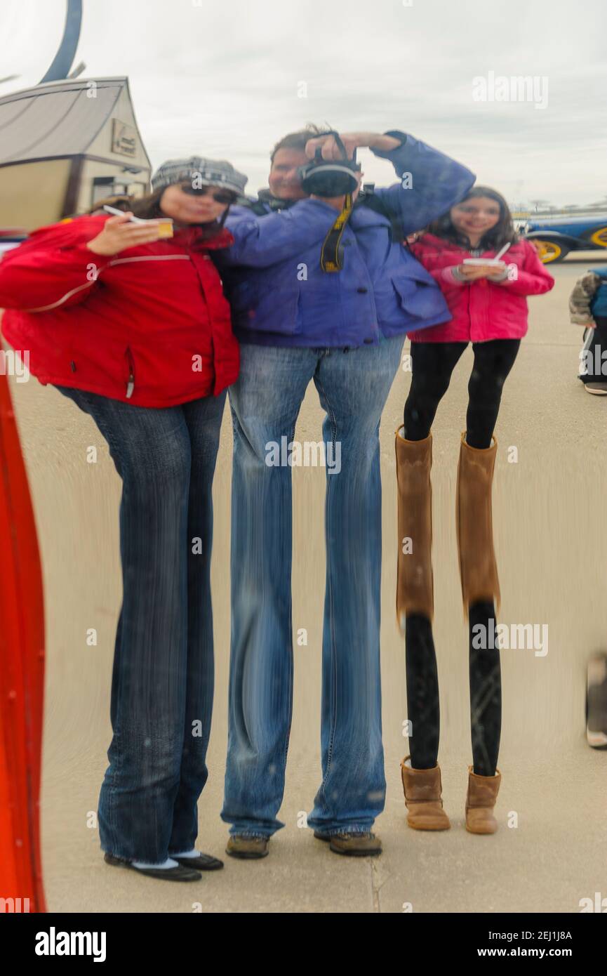 Funhouse mirror, the image of a family is reflected on the surface of a distorting mirror at Navy Pier, Chicago, Illinois. Stock Photo