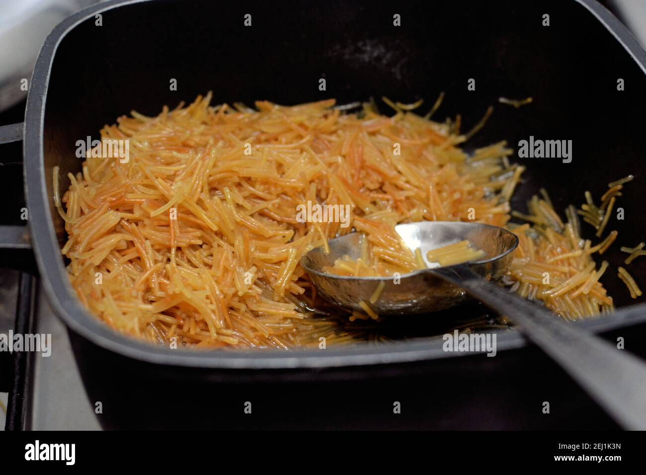 Browned in Butter sweet Egyptian vermicelli cooked with water and sugar in a cooking pot with a ladle,. traditional Egyptian dessert Stock Photo