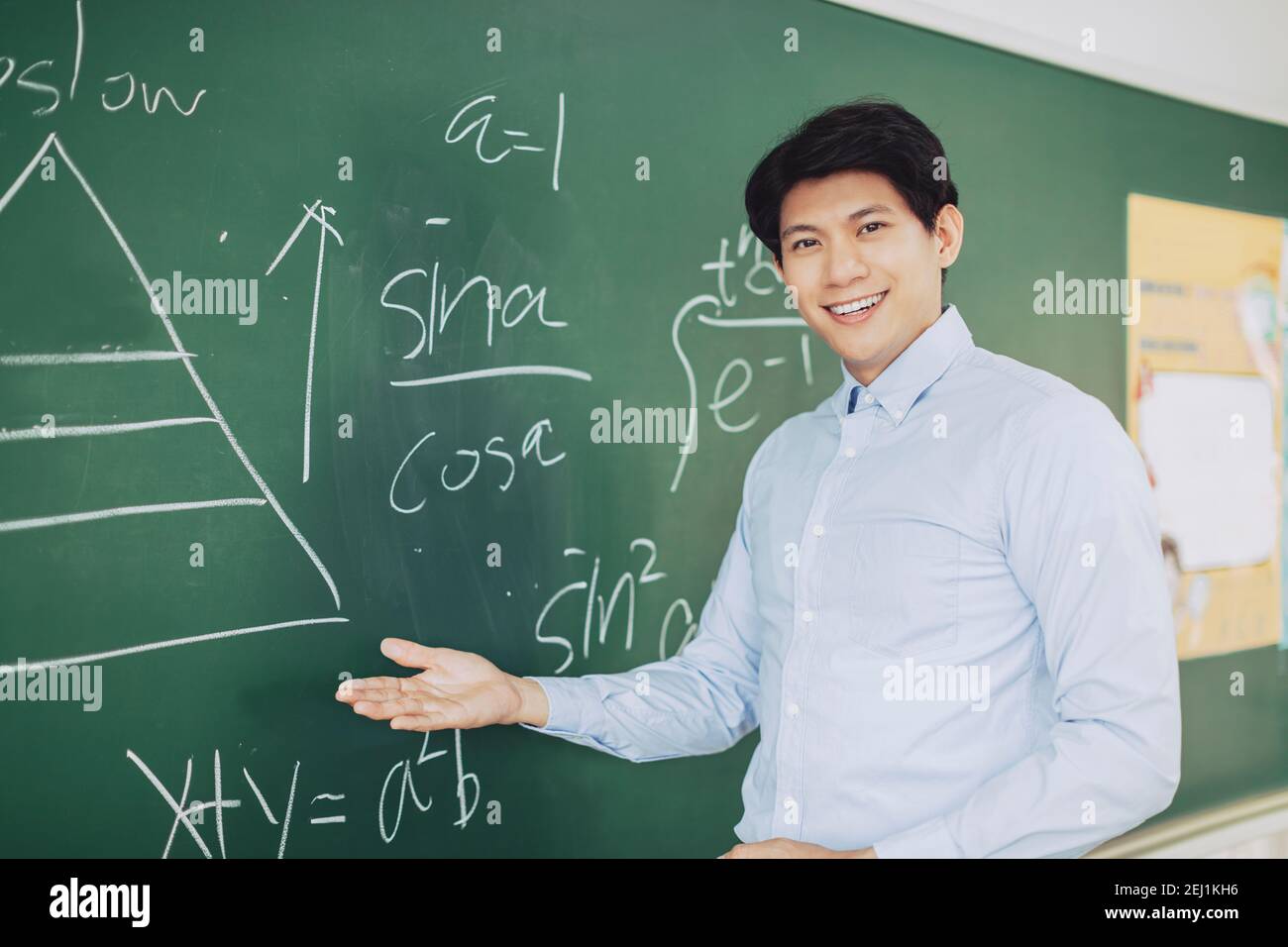 young smiling teacher standing in front of chalkboard Stock Photo - Alamy