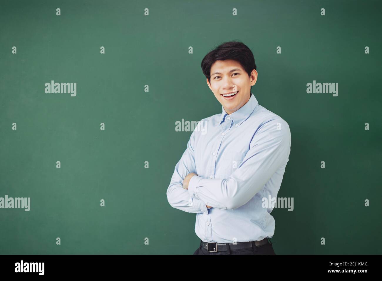 young smiling teacher standing in front of chalkboard Stock Photo - Alamy