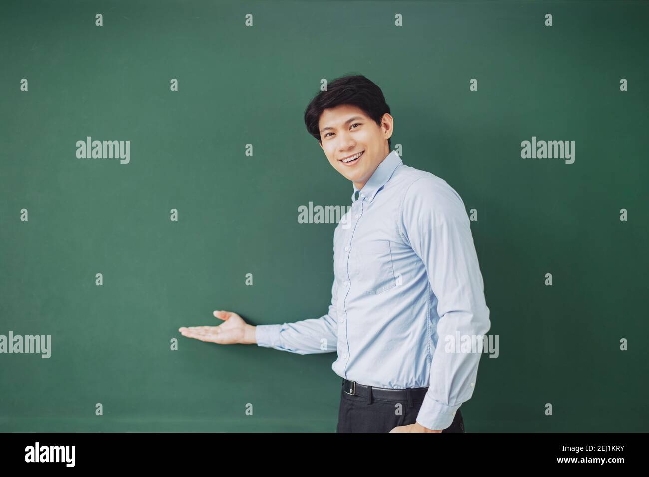 young smiling teacher standing in front of chalkboard Stock Photo - Alamy