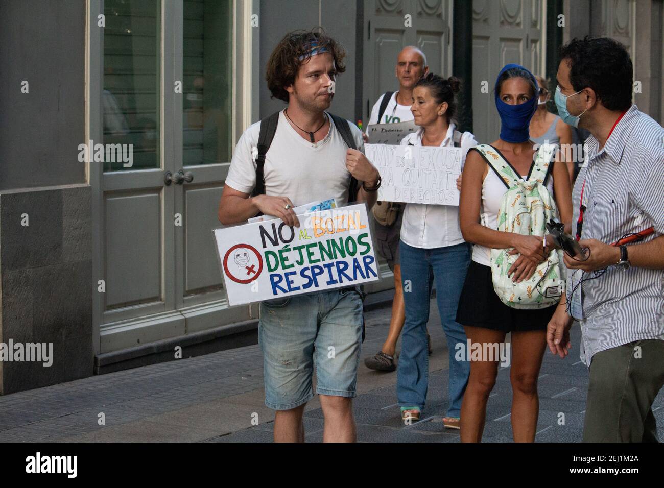 Coronavirus denier is interviewed by a journalist during a demonstration, holds a sign in his hand, that says: 'No to the muzzle, let us breathe' Stock Photo