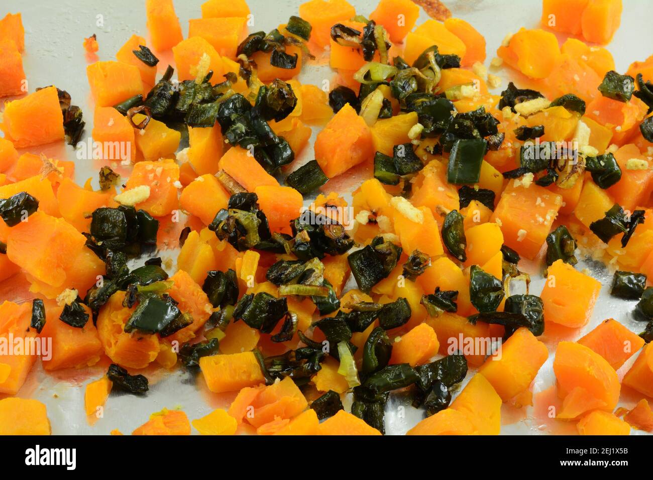 Roasted butternut squash with chopped poblano peppers with spattering of green onions and bread crumbs on aluminum foil Stock Photo