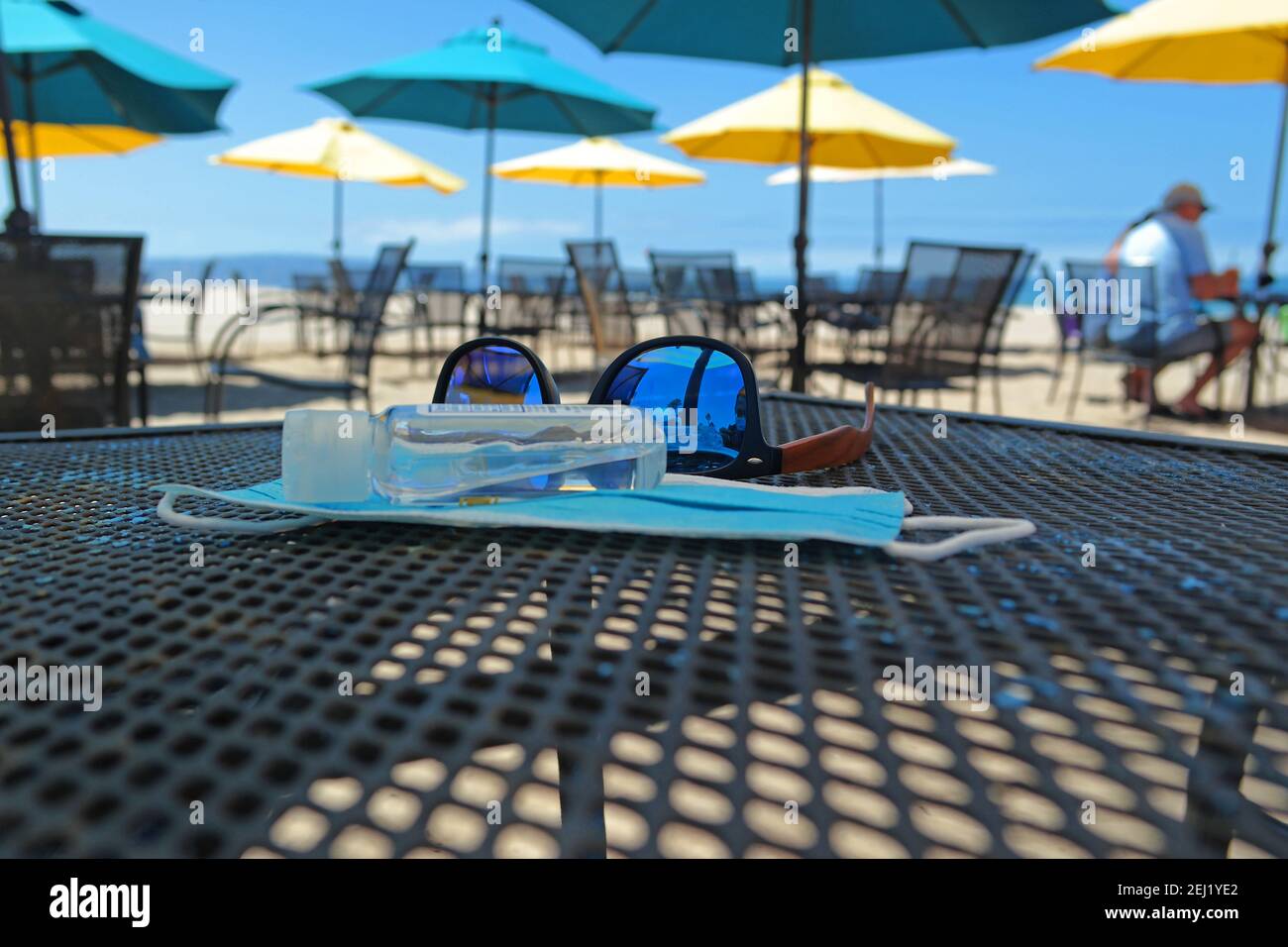 Sunglasses, Hand Sanitizer, and Face Mask on Cafe Table Stock Photo