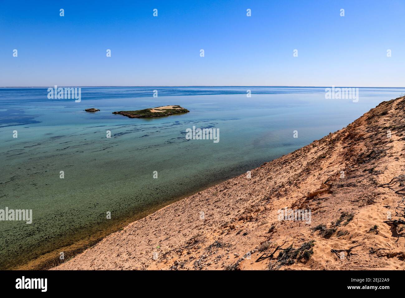 Scenic view of clear calm coastline beneath blue sky and white sand Stock Photo