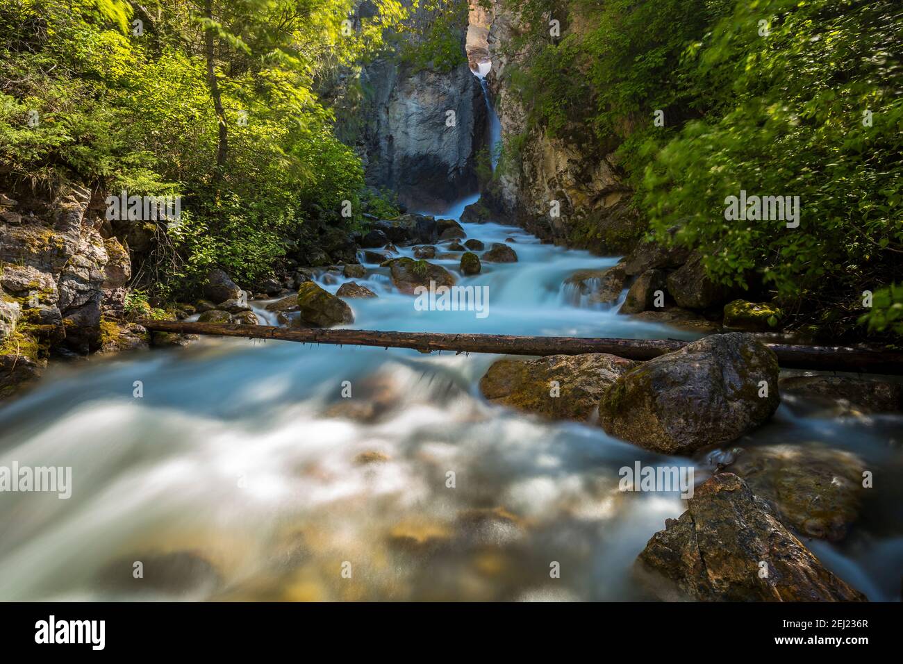 Long exposure of a waterfall and river in a canyon during a sunny day in spring, surrounded by green lush trees and big rocks, Sinclair Falls, Canada Stock Photo