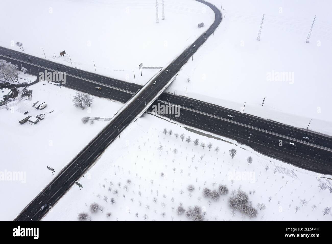 cars drives along a highway overpass during snowfall. aerial view from flying drone Stock Photo