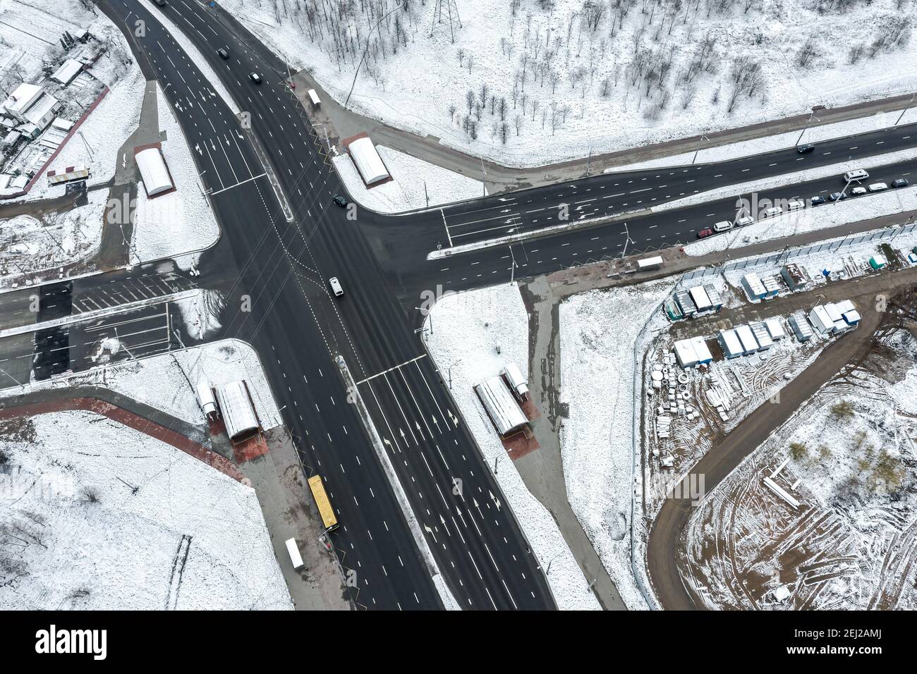 aerial top view of winter cityscape with snow, road intersection and cars traffic Stock Photo