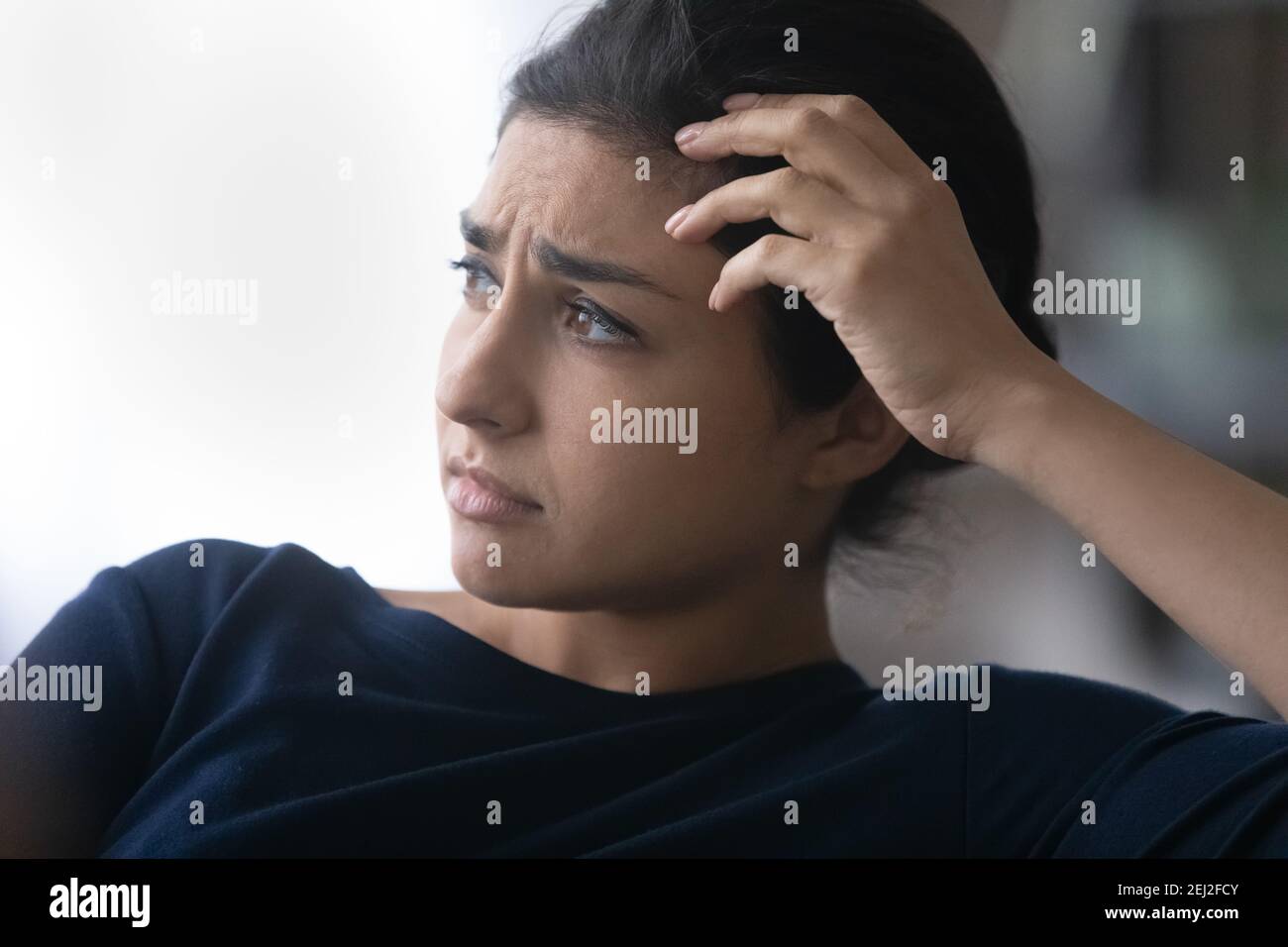 Unhappy Indian woman look in distance feeling lonely Stock Photo