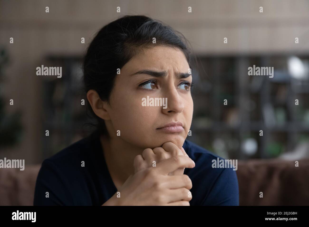 Unhappy Indian woman look in distance feeling lonely Stock Photo