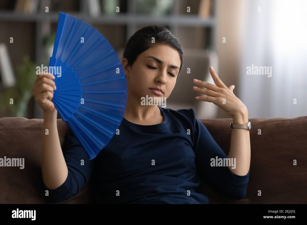 Unwell Indian woman feel overheated use waver Stock Photo