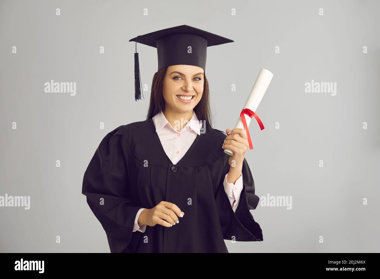 Female graduate proud to have received a diploma and shows it standing ...