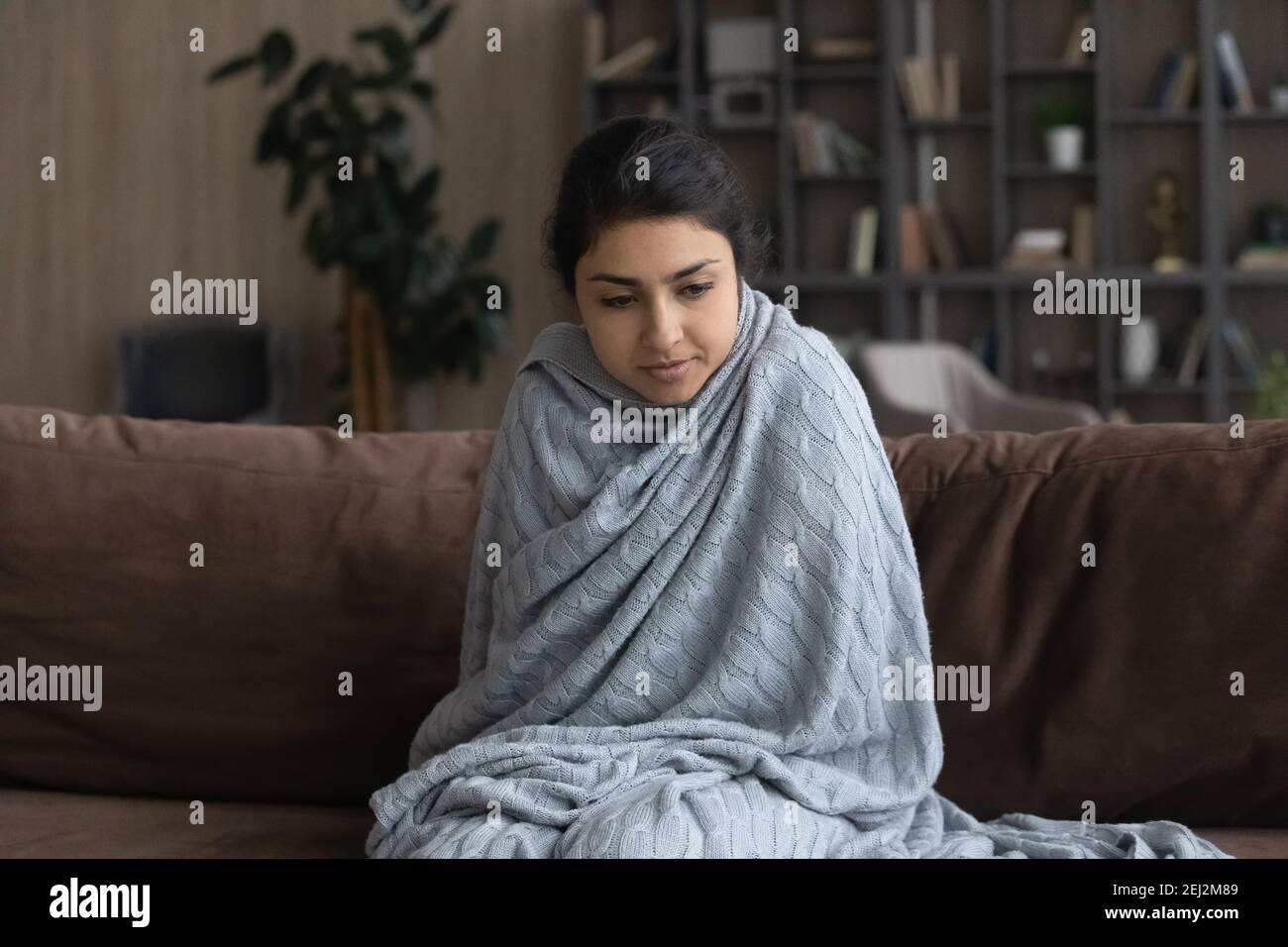 Sick young Indian woman wrapped in blanket feeling unhealthy Stock Photo