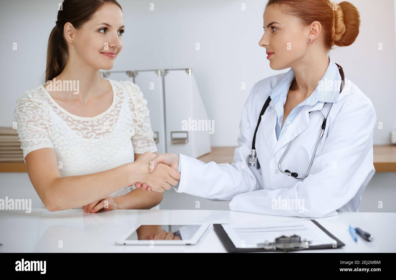 Woman-doctor reassuring her female patient while sitting at the desk ...
