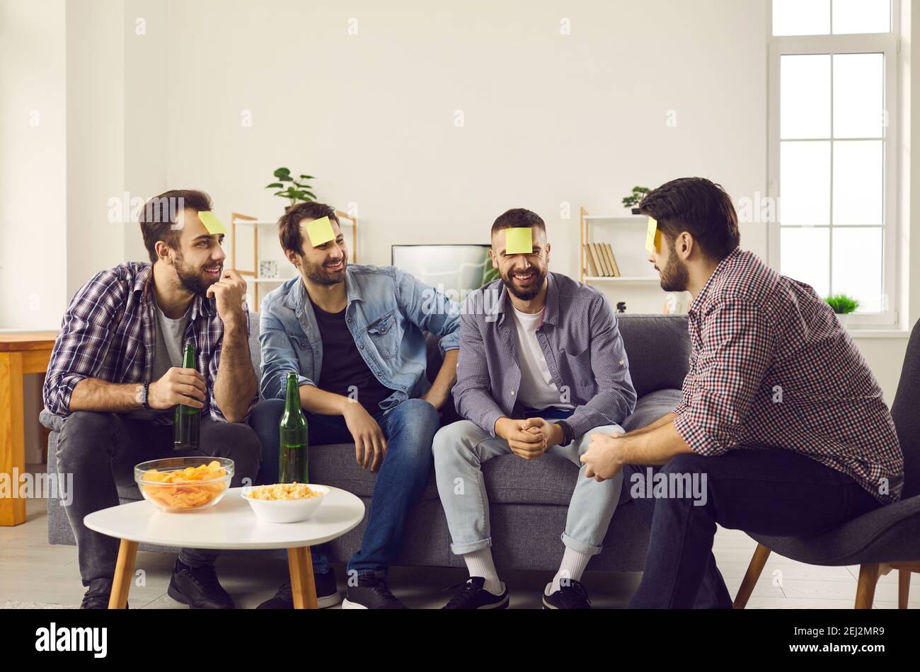 Male friends gathered at home on the weekend and had fun playing the game Who am I. Stock Photo