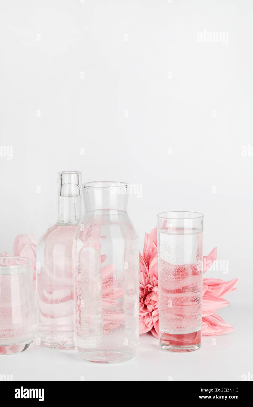pink flowers distorted through water in glasses and bottle on white background. Home decor, eco friendly, relax, gardening concept. copy space Stock Photo