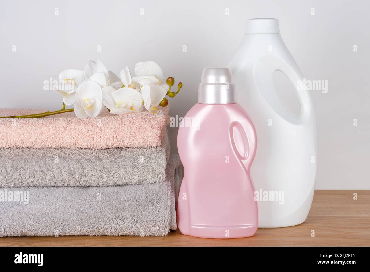 Bottles of detergent and fabric softener with clean towels and orchid