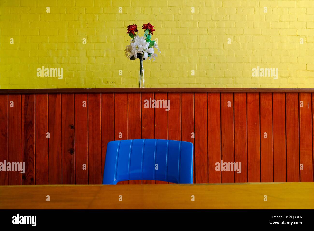 Blue chair and bright yellow wall with a small bouquet of flowers with plenty of copy space. Stock Photo