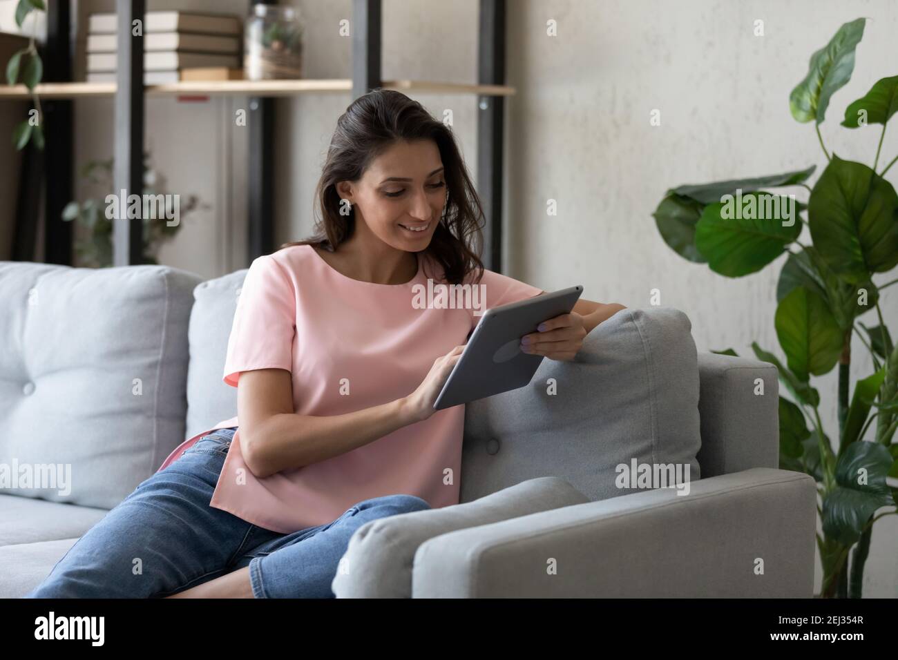 Smiling indian woman relaxing on sofa at home using tablet Stock Photo ...